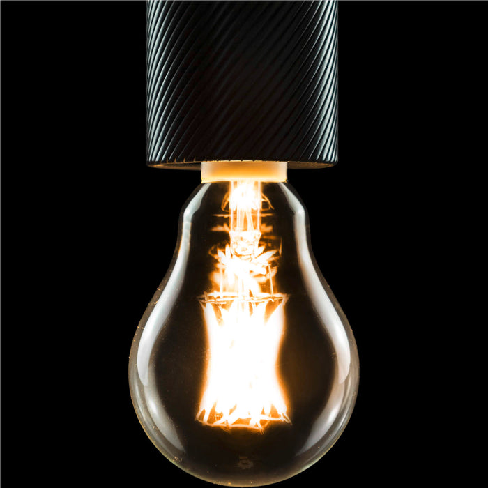 Clear glass light bulb with glowing filament and black textured metal socket.
