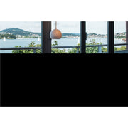 White globe pendant light fixture, hanging in front of a window with a lake view.