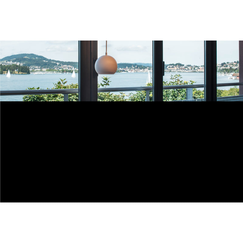 White globe pendant light fixture, hanging in front of a window with a lake view.