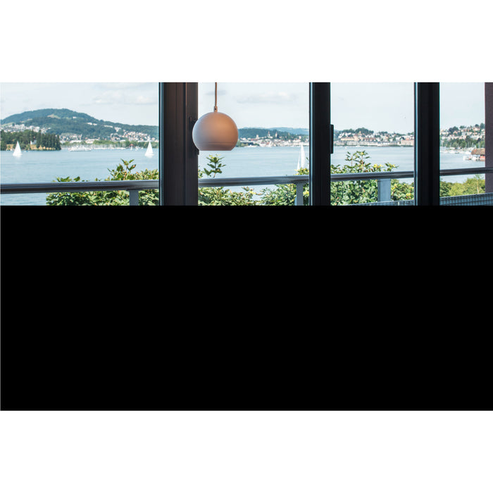 White globe pendant light fixture, hanging in front of a window with a lake view.