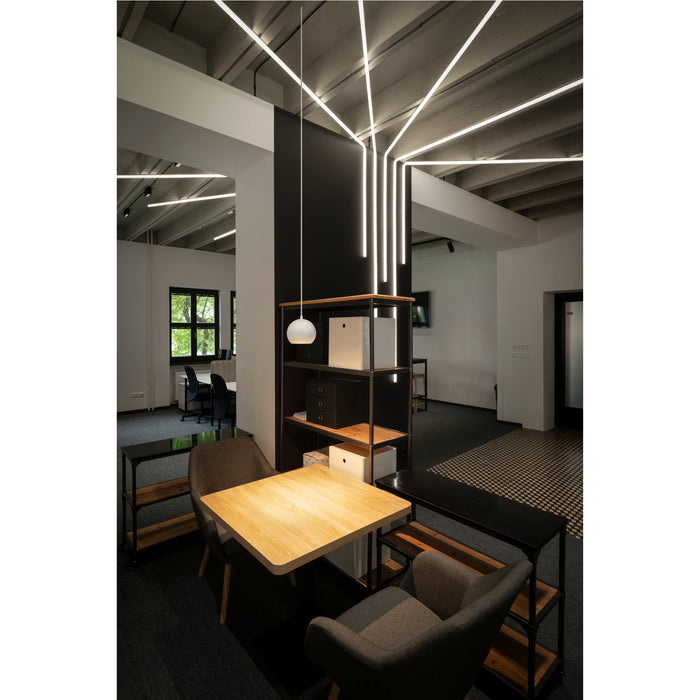 Modern office interior with linear LED ceiling lights, wood table, gray chairs, and black metal shelving.