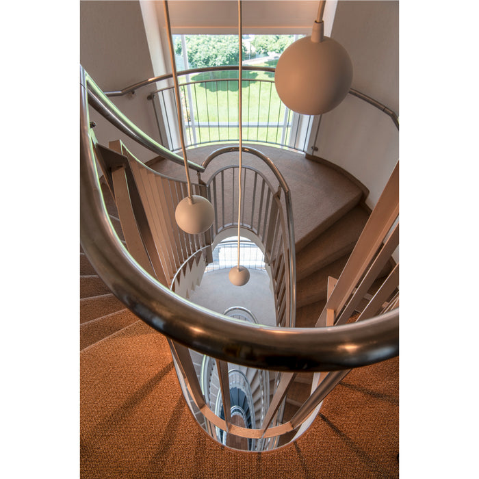 Spiral staircase with carpeted steps, stainless steel railing, and white pendant lights.