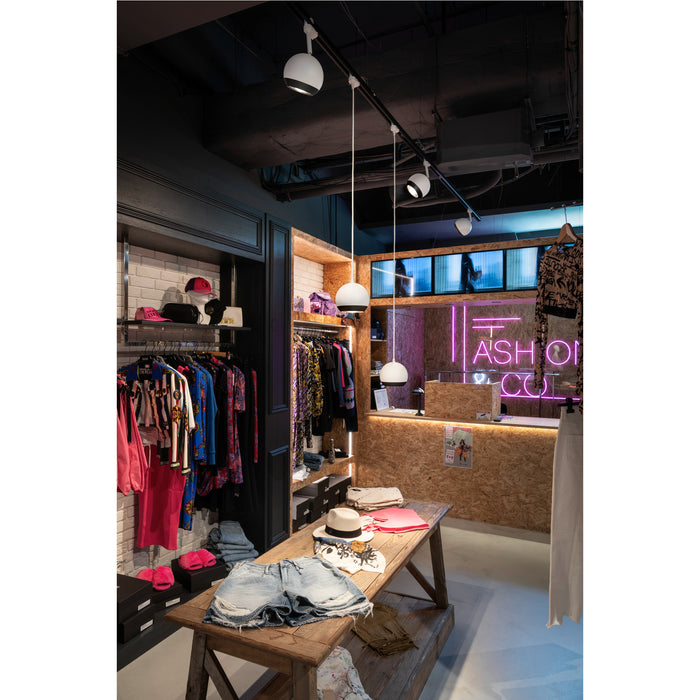 Clothing store interior with wood table, white pendant lights, and neon sign.