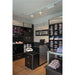 Cafe Coton store interior with dark wood shelving displaying shirts and ties, white brick wall, and white and gold track lighting.