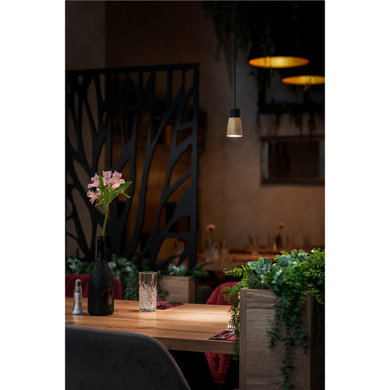 Hanging pendant light fixture, metal and wood, with black and gold finish, over restaurant table.