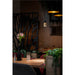 Hanging pendant light fixture, metal and wood, with black and gold finish, over restaurant table.
