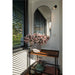 Black framed oval mirror above wood and metal console table with gray vase and pink flowers.