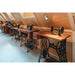 Antique sewing machines with wood tops and ornate black cast iron bases in a bright attic space.