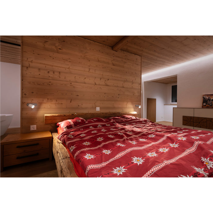 Bedroom with wood paneling, rustic wood bed frame, red floral duvet cover, and wood nightstand.
