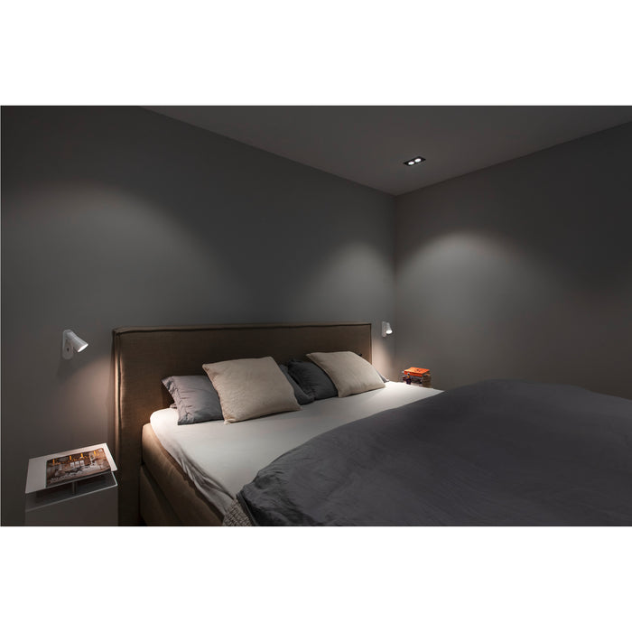 Bedroom with wall-mounted white reading lights illuminating the bed.