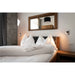 Bedroom with wood bed frame, white linens, and wood-framed mirror.