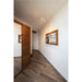 Hallway with wood-look tile floor, wood door, framed mountain print, and white ceiling-mounted spotlight.