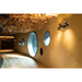 Black metal wall-mounted spotlight with three adjustable heads, illuminating a textured gold wall in a modern interior.