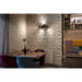 Black metal track lighting fixture, surface mounted on a white brick wall in a restaurant setting.
