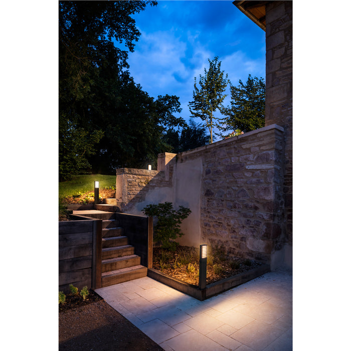 Dark bronze finish path light illuminating stone steps and patio at dusk.