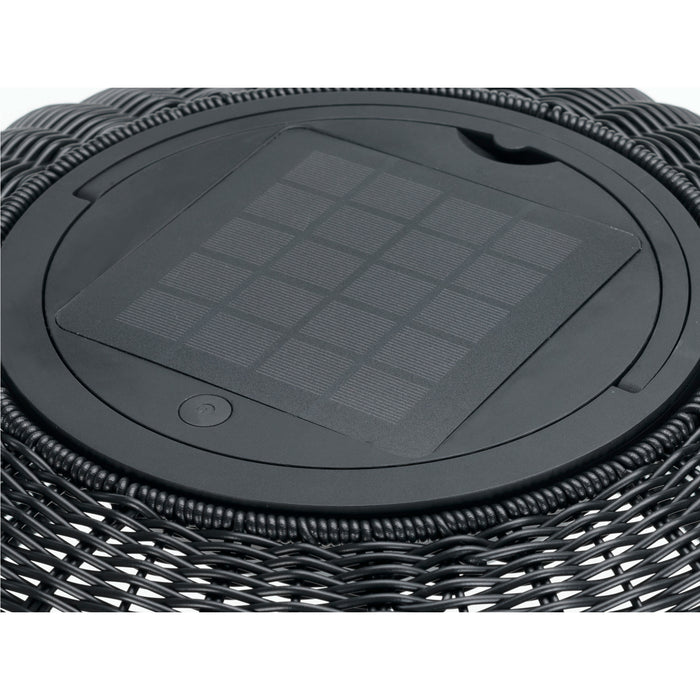 Close-up of a black wicker outdoor solar light with a solar panel on top.