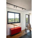 Modern room interior with black track lighting, red metal cabinet, brass telescope, and cane rocking chair.