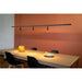 Black metal track lighting with three cylindrical spotlights, suspended over a wooden dining table.