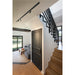 Modern interior with black track lighting, black metal staircase railing, gray door, and light wood stairs.