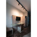 Hotel room interior with wall-mounted TV, glass desk, white leather chair, wood veneer paneling, and black track lighting.