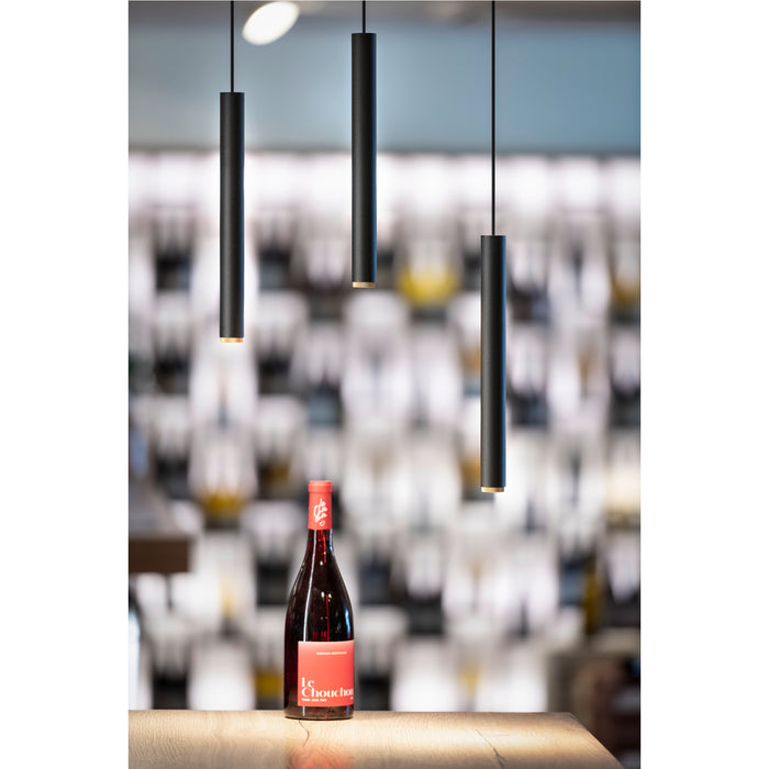 Three black, cylindrical pendant lights with gold accents, suspended over a wooden surface with a wine bottle.