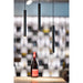 Three black, cylindrical pendant lights with gold accents, suspended over a wooden surface with a wine bottle.