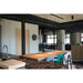 Cylindrical pendant lights, copper finish, suspended above a long wooden table in a modern office space.