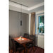 Black cylinder pendant light fixture mounted on track lighting above dining table.