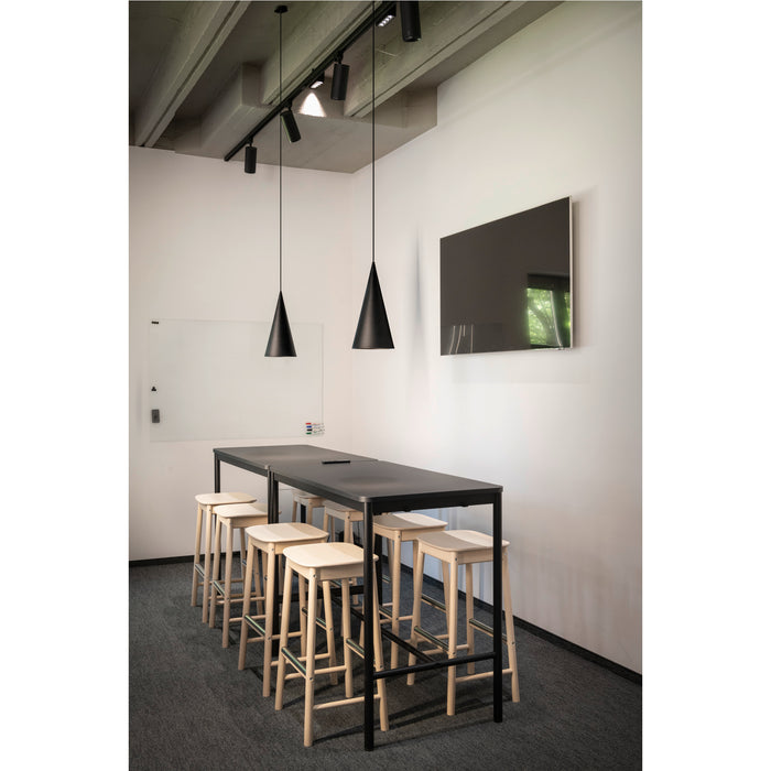 Modern office space with black metal table, light wood stools, black pendant lights, and wall-mounted whiteboard and TV.