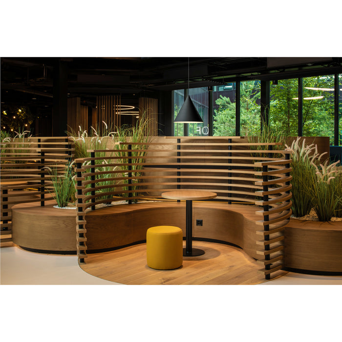 Modern office lounge area with curved wood benches, round table, yellow ottoman, and black pendant light.