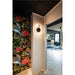 Interior with floral wallpaper, black ceiling tiles, and a round black and white LED wall sconce.