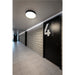 Hallway with black doors, concrete block walls, tile floors, and a round, ceiling-mounted light fixture.