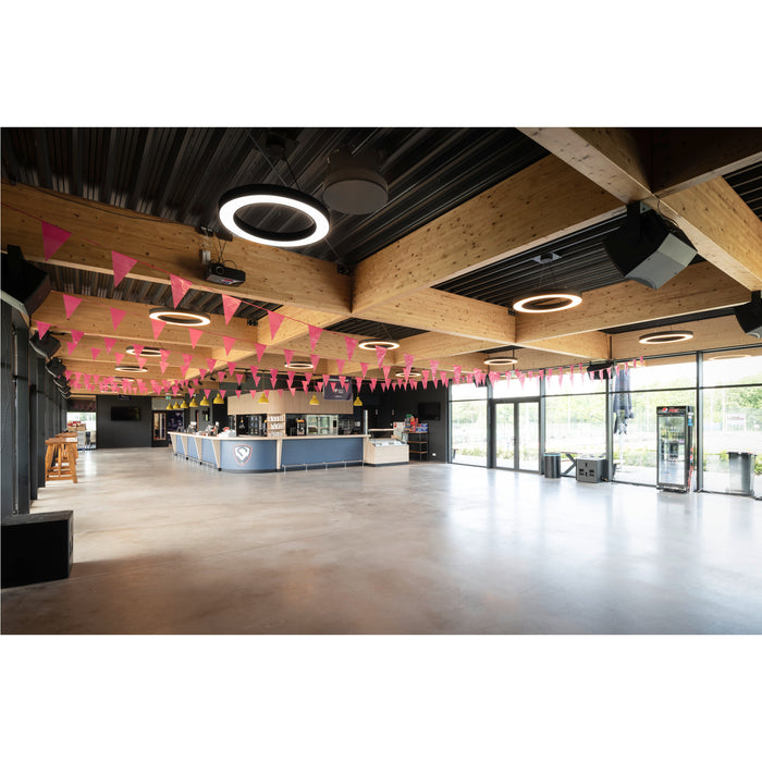Large event space with wood beams, ring lights, pink pennants, and a blue bar.