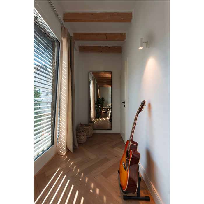 Hallway with herringbone wood floor, full-length mirror, guitar on stand, window with blinds, and exposed wood beams.