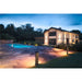 Black bollard lights illuminate a stone patio and pool area at dusk.