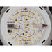 Close-up of a round, white LED module with yellow LEDs, various electronic components, and black and red wires.