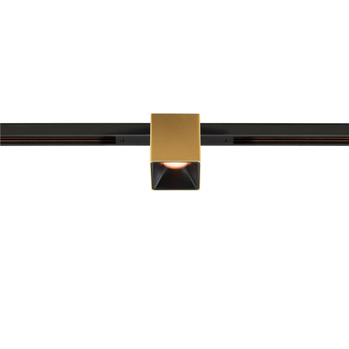 Gold finish square track lighting fixture mounted on black track.