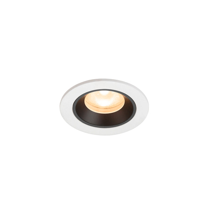 Recessed ceiling light fixture with a white metal finish and black trim, featuring a warm LED bulb for ambient lighting.
