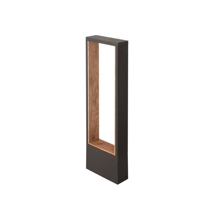 Modern bollard light fixture, dark gray finish with wood grain interior, ground mount.