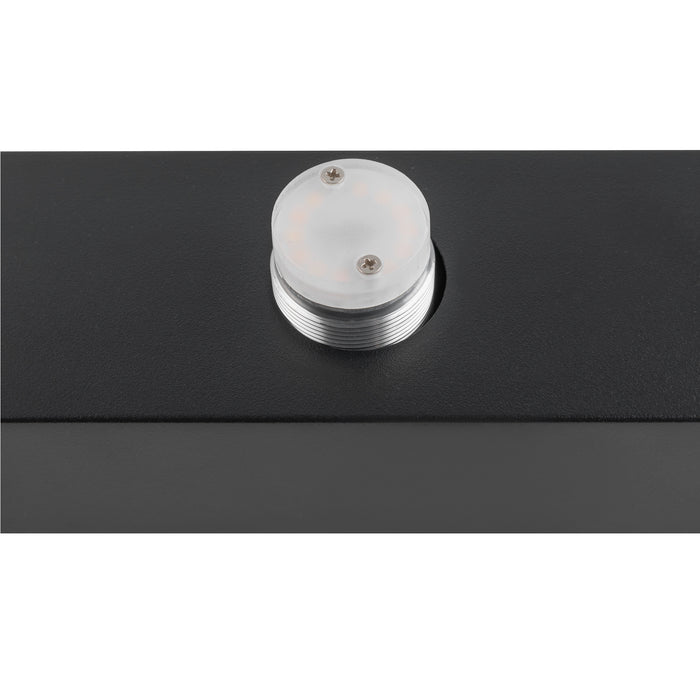 Close-up of a black metal box with a clear, round LED light fixture mounted on top.