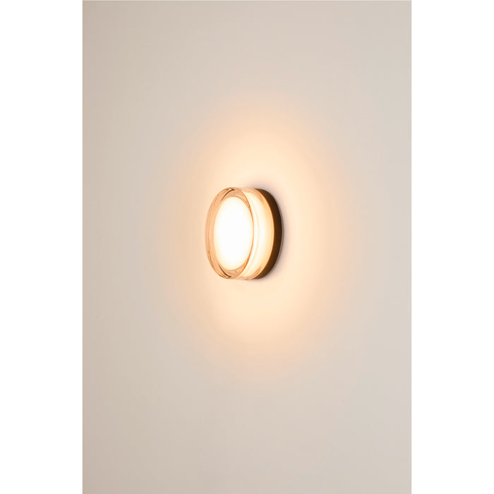 Round glass wall sconce with warm light.