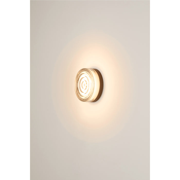 Clear glass wall sconce with bronze backplate, mounted.