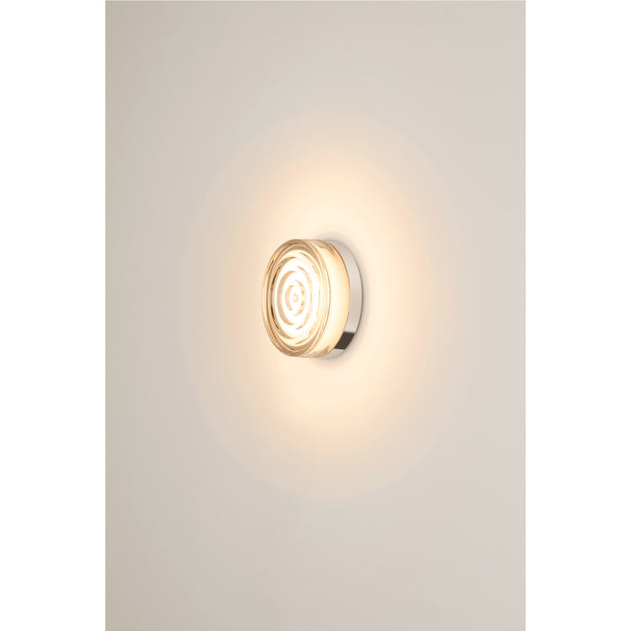 Wall-mounted light fixture with clear glass diffuser and polished chrome base.