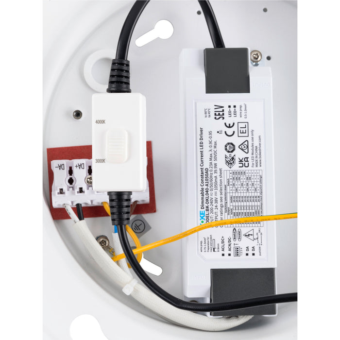 Internal view of a white surface-mounted LED fixture showing wiring, a color temperature switch, and a dimmable constant current LED driver.