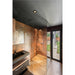 Modern bathroom with copper-toned tile, black sink and vanity, glass shower enclosure, and view to the outside.