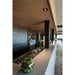 Modern bar interior with speckled gray countertop, wood ceiling, black columns, and glass terrarium.