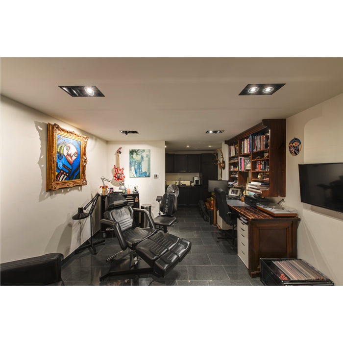 Tattoo studio interior with black leather chairs, dark wood desk and cabinets, and artwork.