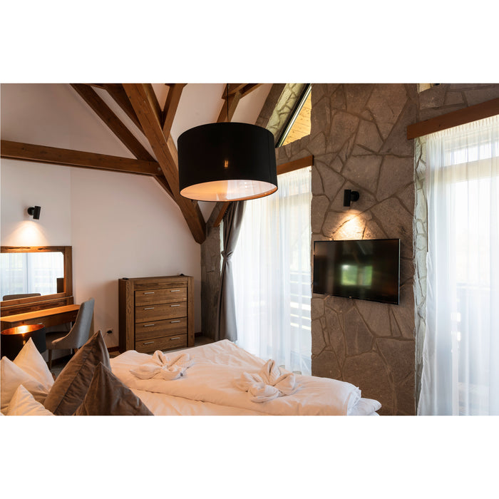 Bedroom with wood beams, stone accent wall, black pendant light, and TV.