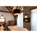 Bedroom with wood beams, stone accent wall, black pendant light, and TV.