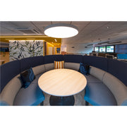 Office booth with blue fabric panels, light wood table, and gray upholstered seating.